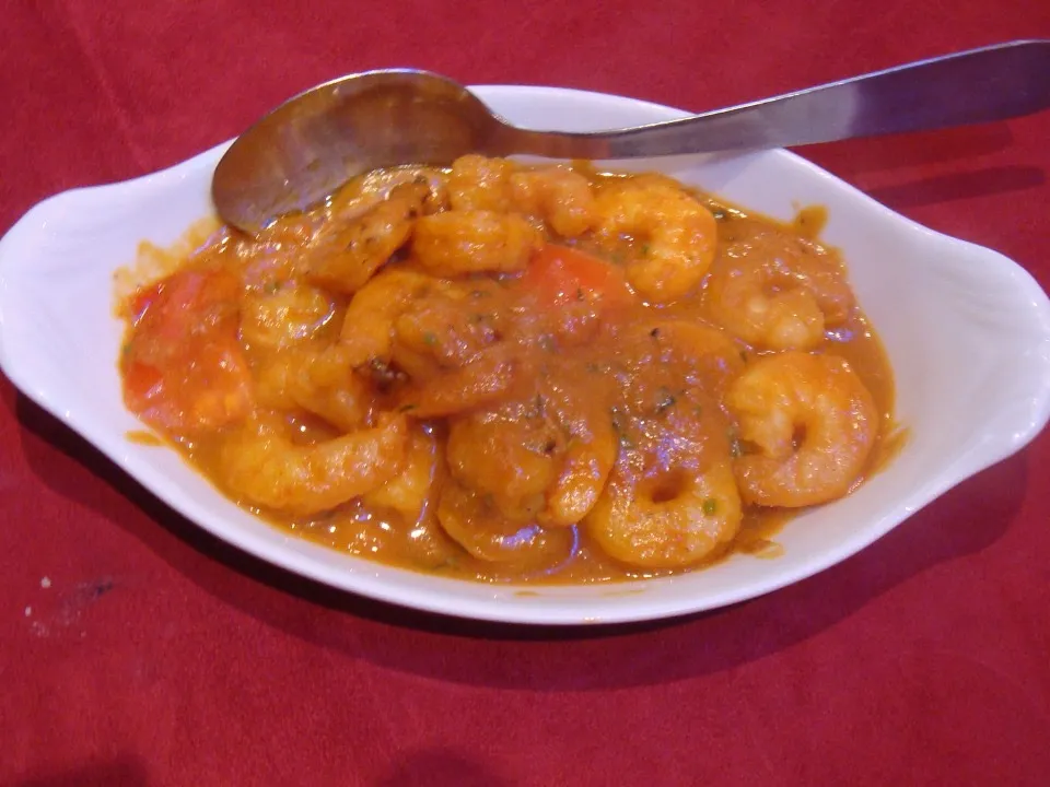 Crevettes massala dans une sauce tomatée, servies en plat ovale.