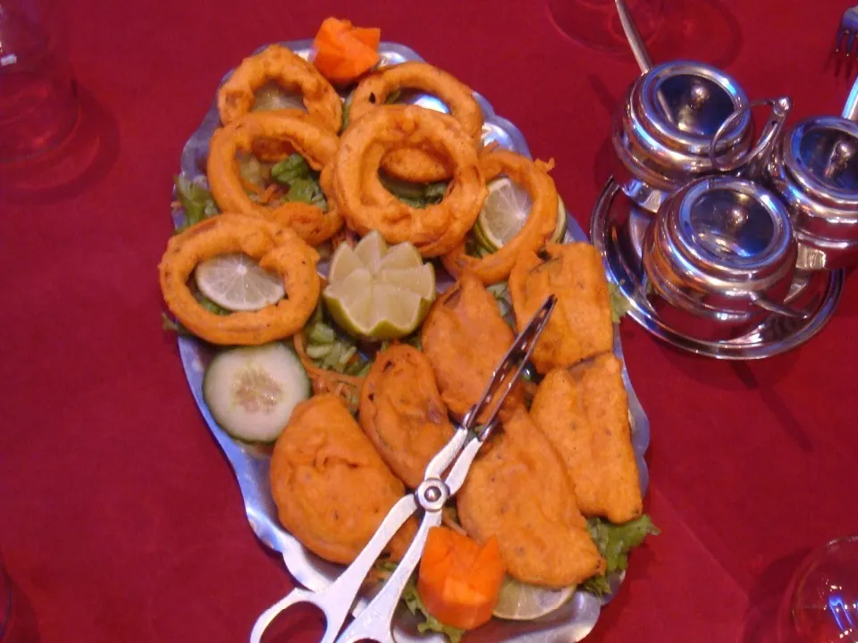 Assortiment de beignets et rondelles d’oignon frites servis sur un plateau.